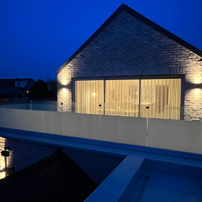 frame-one Image of a newly installed frameless glass balcony in Rhosneigr, Anglesey, featuring 21.5mm toughened laminated glass with partial frosting, overlooking a scenic coastal view