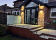 Frameless glass balustrade installed on a garden patio in Altrincham, featuring 17.5mm toughened laminated glass and stainless steel spigots.