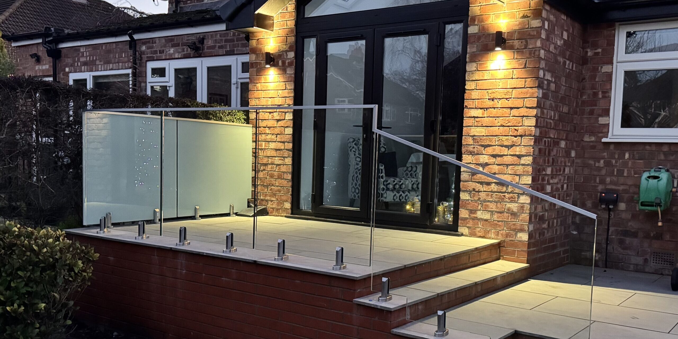 Frameless Glass Balustrade Frameless glass balustrade installed on a garden patio in Altrincham, featuring 17.5mm toughened laminated glass and stainless steel spigots.