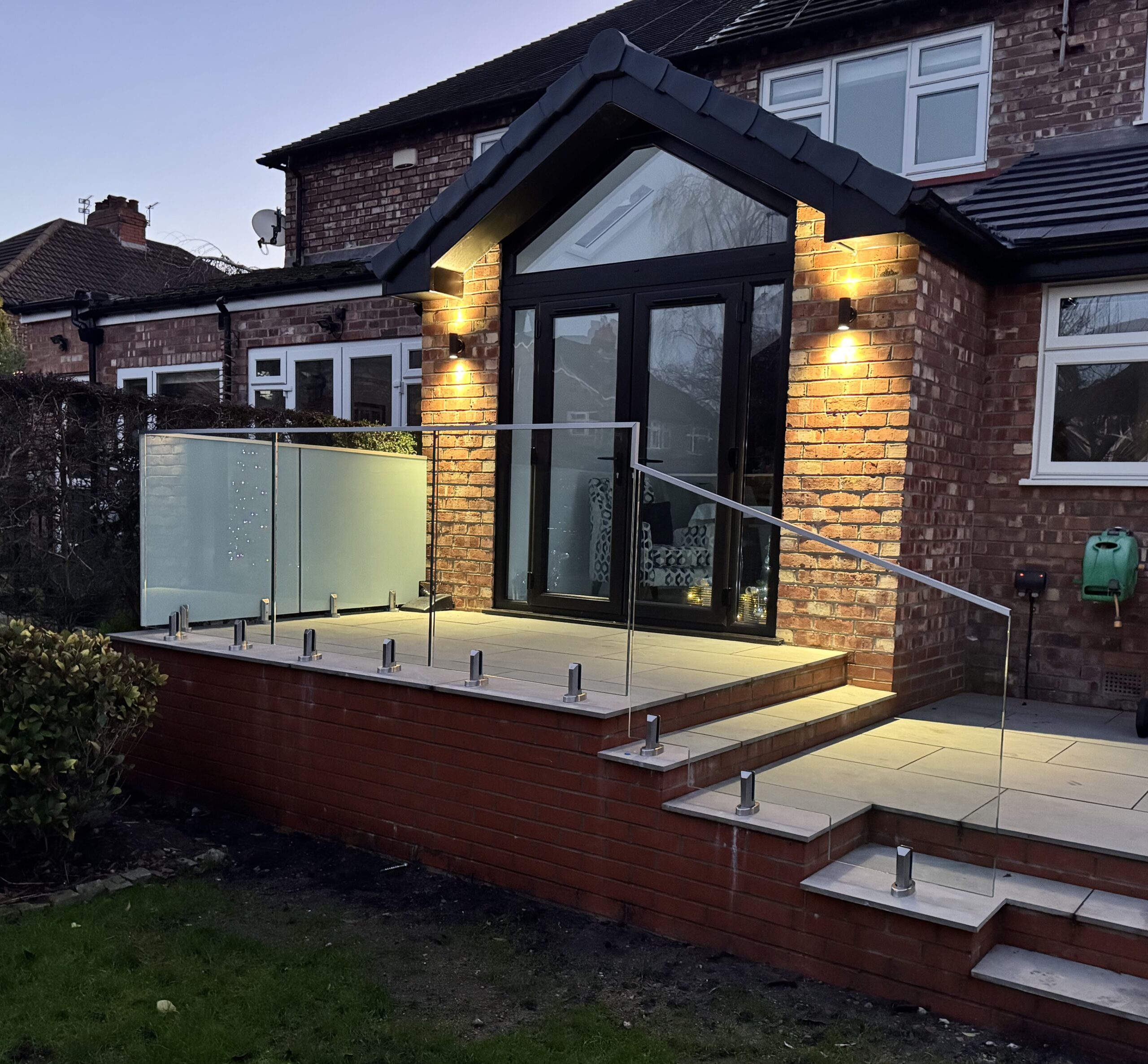 Frameless Glass Balustrade Frameless glass balustrade installed on a garden patio in Altrincham, featuring 17.5mm toughened laminated glass and stainless steel spigots.