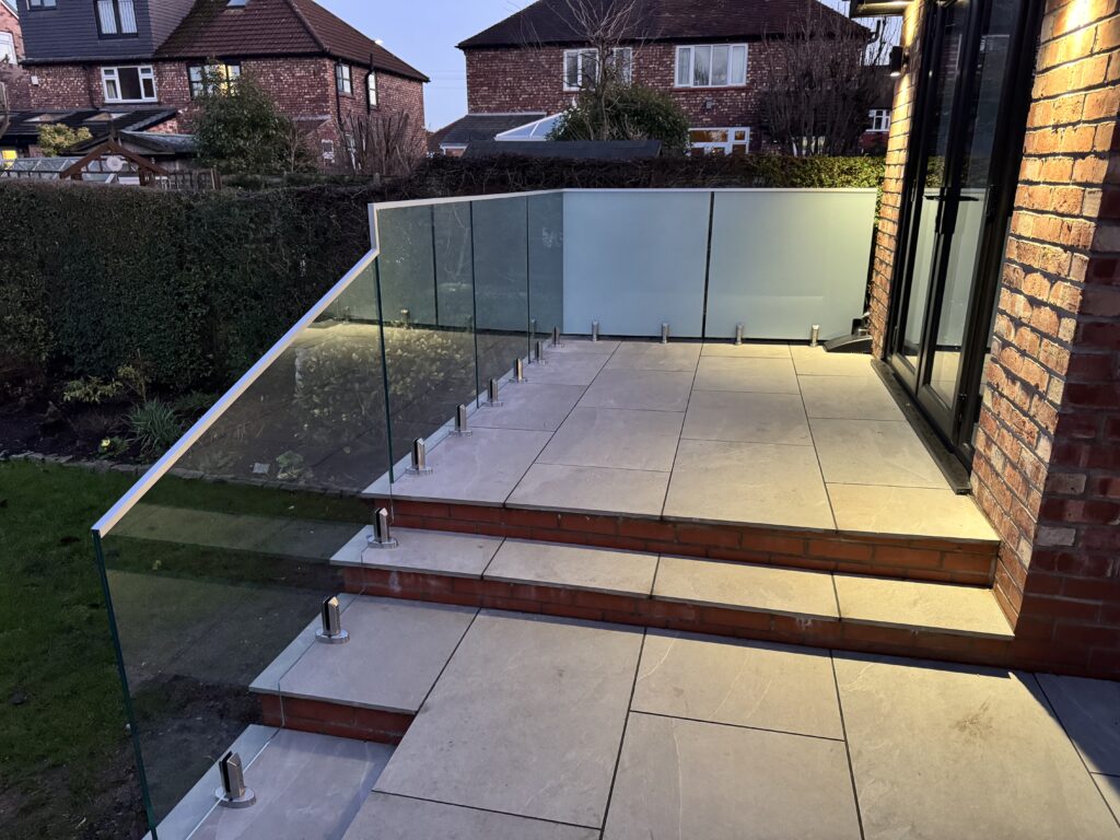 Detail shot of the toughened laminated glass panel and base spigot fixing on a tiled patio, demonstrating precision installation and durability.