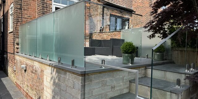 IMG_8934 Glass balustrade installation in Salford featuring 17.5mm toughened laminated glass panels with structural spigots and aluminium capping rail by NW Fabrications