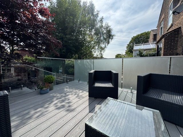 Modern glass balustrade with obscure glass privacy panels and continuous aluminium capping rail installed on residential balcony in Salford