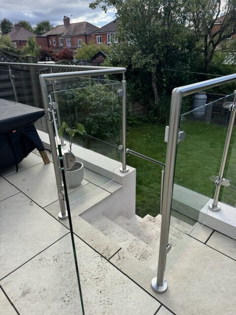 Magnetic latch detail on self-closing glass gate with 316-grade stainless steel frame in Chadderton